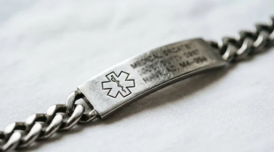 Close-up view of a medical alert bracelet showing engraved emergency health information on metal surface